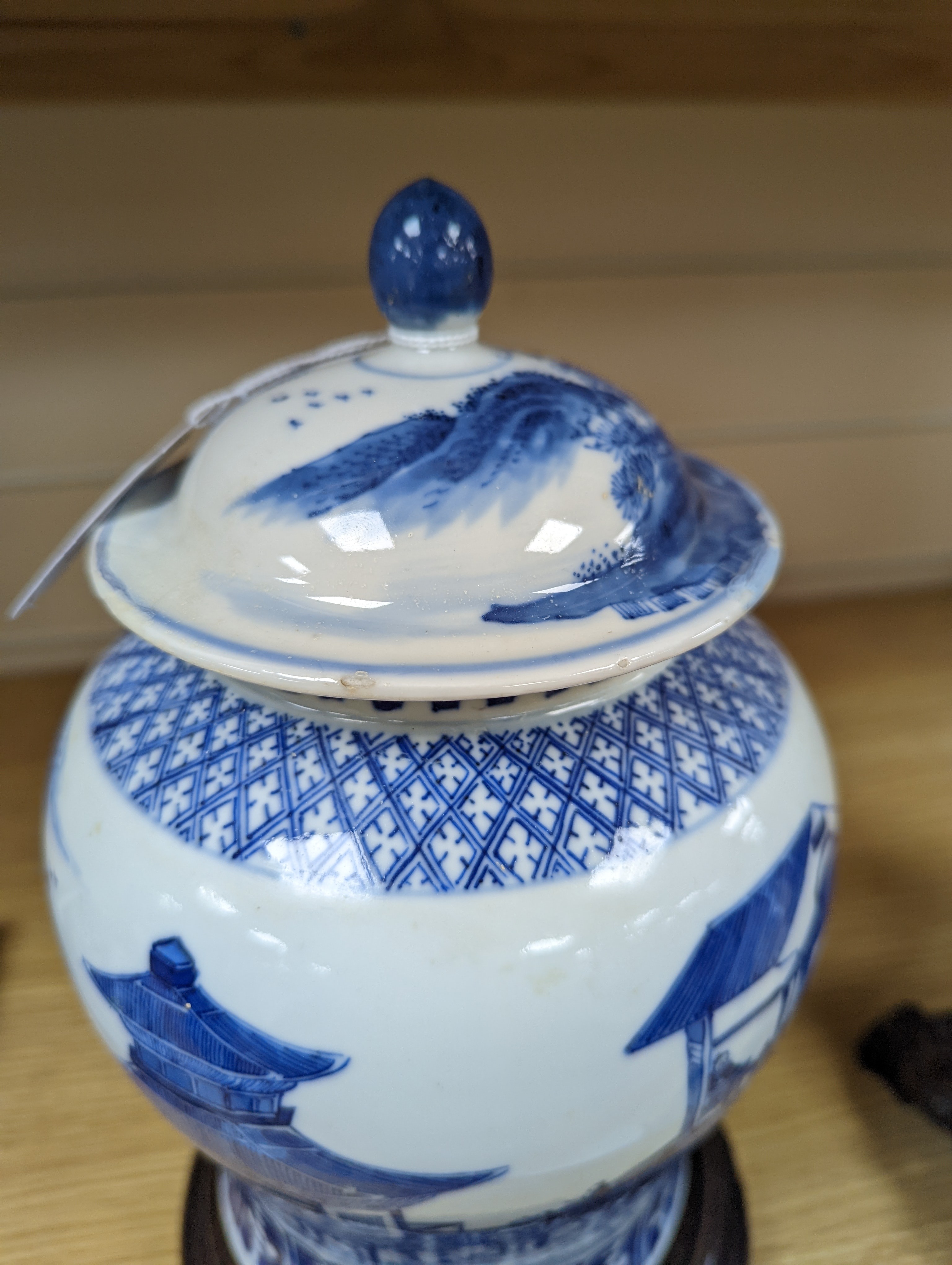 A late 19th / early 20th century Chinese blue and white landscape jar and cover, wood stand 30cm total height